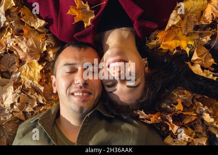 Draufsicht auf das Paar, das in Herbstblättern liegt. Liebe und Glück Konzept. Stockfoto