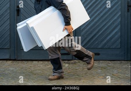 Mann läuft, hält Stapel von Kisten, Seitenansicht Stockfoto