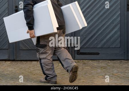 Mann läuft, hält Stapel von Kisten, Seitenansicht Stockfoto