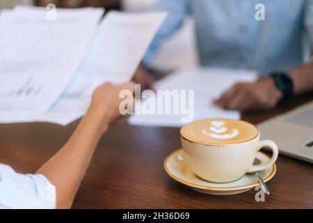 Nahaufnahme eines nicht erkennbaren Geschäftsmanns und einer Geschäftsfrau, die über die Diskussion und Überprüfung von Papierdokumenten sprach. Stockfoto