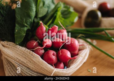 Rettich in Leinwand Lebensmittelbeutel. Gemüse in wiederverwendbaren Öko-Baumwollbeuteln auf Holztisch. Zero Waste Shopping-Konzept. Kunststoffartikel Stockfoto