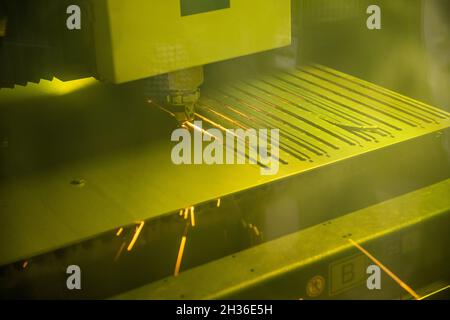 Ein robotischer Laserschneider schneidet in einer Fertigungsstätte Löcher in ein Stahlteil, um Möbel für ein kommerzielles Unternehmensbüro zu produzieren Stockfoto