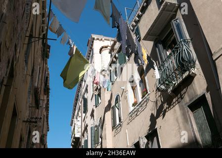 VENEDIG, ITALIEN - 03. Oktober 2021: Die Wäsche hängt an einer Linie zwischen den Gebäuden in der Mitte der Straße in Venedig, Italien Stockfoto