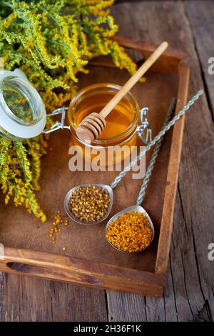 Pollengranulat von Bienen. Frischer Honig auf Holztisch. Produkthintergrund für Stillleben. Holzlöffel mit kleinem Glas Nahaufnahme. Öko-Lebensmittel. Selektiver Fokus, Kopierbereich. Stockfoto