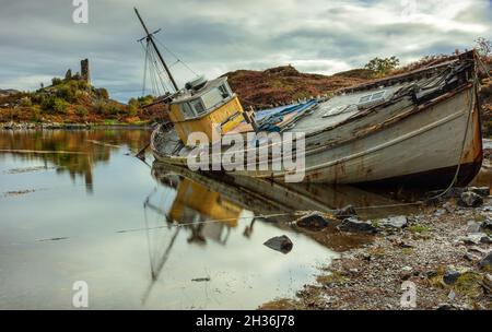 Verlassenes Boot auf Loch Alsh, Isle of Skye, Schottland, mit den Ruinen von Castle Moil im Hintergrund Stockfoto