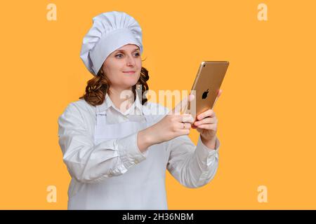 Glückliche Frau mit ipad Apple Tablet auf gelbem Studiohintergrund, Kopierraum - Moskau, Russland, 20. Oktober 2021 Stockfoto