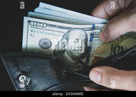 Geldbörse mit Dollars in den Händen. Viel Geld in der Geldbörse. Zahltag. Einnahmen aus den Finanzmärkten. Ein Geschäftsmann demonstriert seinen Gewinn. Stockfoto