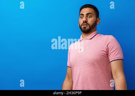 Junger Mann nervös und verängstigt Blick auf etwas vor blauem Hintergrund Stockfoto