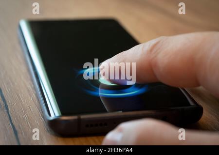 Nahaufnahme der männlichen Hand mit Smartphone Fingerabdruck entsperren App. Männliche Finger drückt auf dem Smartphone-Bildschirm, um per Fingerabdruck zu entsperren. Stockfoto