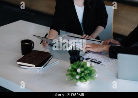 Nahaufnahme von jungen Geschäftsleuten, die Daten aus Papierkram am Computer analysieren, während sie im Büro arbeiten. Gesprächskonzept treffen Stockfoto