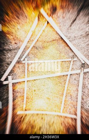 Doppelbelichtung eines Streichholzhauses auf Betonhintergrund mit auskommenden Flammen Stockfoto