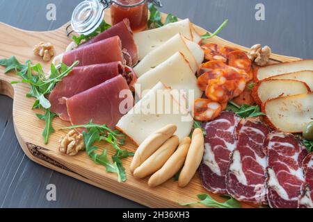 Sehr farbenfrohe Tapas-Tafel mit Wurstwaren und Käse. Dekoriert mit Rucola und Walnüssen. Weinsnacks. Stockfoto