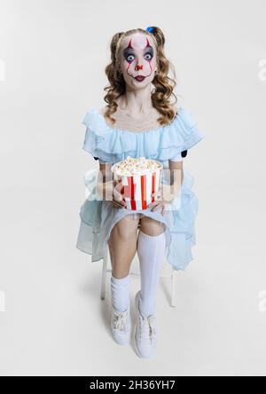 Konzeptionelle Bild von jungen Mädchen trägt Halloween-Kleid von tanzenden Clown mit gruseligen Make-up isoliert auf grauem Hintergrund. Stockfoto