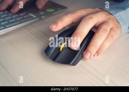 Geschäftsmann in elegantem Anzug und mit Computermaus in Nahaufnahme am Schreibtisch im Büro. Geld verdienen online. Geld auf Klicks. Werbung auf der Inter Stockfoto