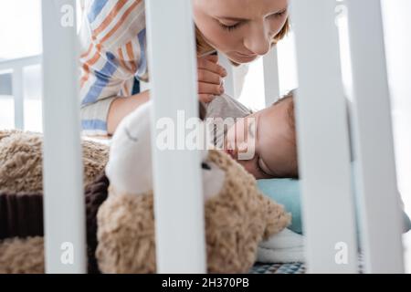 Mutter schaut auf das schlafende Baby mit Down-Syndrom in der Krippe Stockfoto