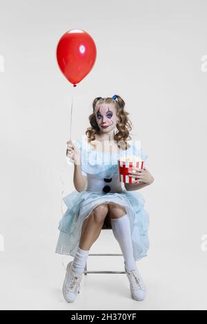 Konzeptionelle Bild von jungen Mädchen trägt Halloween-Kleid von tanzenden Clown mit gruseligen Make-up isoliert auf grauem Hintergrund. Stockfoto