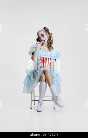 Konzeptionelle Bild von jungen Mädchen trägt Halloween-Kleid von tanzenden Clown mit gruseligen Make-up isoliert auf grauem Hintergrund. Stockfoto