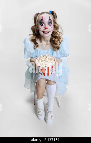 Konzeptionelle Bild von jungen Mädchen trägt Halloween-Kleid von tanzenden Clown mit gruseligen Make-up isoliert auf grauem Hintergrund. Stockfoto