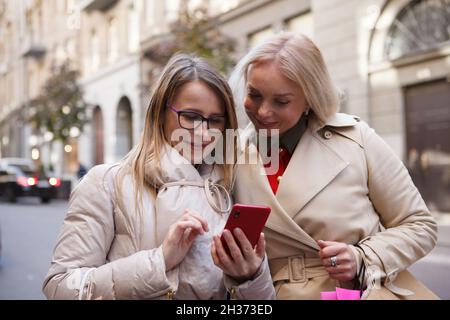 Zwei reife Frauen, die gemeinsam Smartphone im Freien benutzen Stockfoto