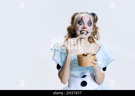 Nahaufnahme mystisch blonde Mädchen in halloween Make-up und gruselige Gesichtsausdruck essen Gelee Süßigkeiten isoliert auf grauem Hintergrund Stockfoto