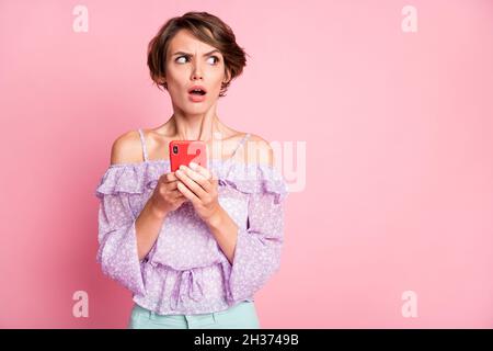 Foto von jungen schockiert überrascht überrascht Mädchen mit Smartphone-Look Copyspace isoliert auf rosa Hintergrund Stockfoto