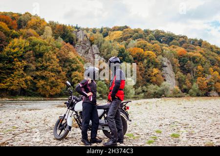 Ein paar Biker fahren im Herbst mit dem Motorrad. Motorradfahrer genießen die herbstliche Landschaft in den Bergen und ruhen sich im Wald aus Stockfoto