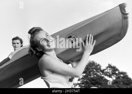 Junge Frau trägt im Badeanzug lachend ein Boot/Klepper T6, Deutschland 1930er Jahre. Junge Frau im Badeanzug mit einem Boot/Klepper T6 Lachen, Deutschland 1930. Stockfoto