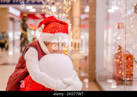 Boys in Santas Hut schaut durch das Fenster auf dem Markt in den Laden. Platz zum Kopieren, Platz für Text, Banner Stockfoto