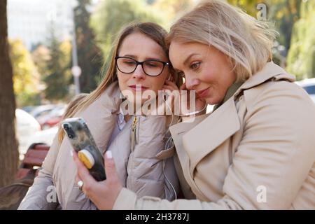 Ältere Frauen, die im Freien Kopfhörer mit Smartphone verwenden Stockfoto