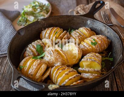 Gebackene Kartoffeln mit Butter und geschmolzenem Käse. Serviert in einer gusseisernen Pfanne für eine Beilage Stockfoto