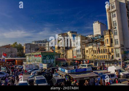 Eminonu, Istanbul, Türkei-Oktober-Samstag-2021: Wolkiges Wetter, geparkte Autos.Menschen, die zwischen alten Häusern spazieren. Graffiti-Zeichnung. Golden Horn Metro Bridge Stockfoto