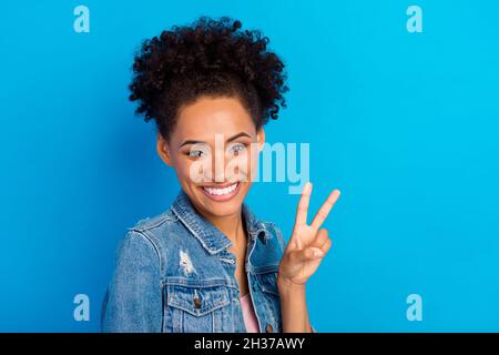 Foto von fröhlich positive glücklich afro amerikanische Frau zeigen V-Zeichen gute Stimmung isoliert auf blauem Hintergrund Stockfoto