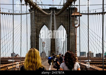 NEW YORK, NY, USA - 27. APRIL 201: Touristen wandern auf der belebten Brooklyn Bridge auf Manhattan. Stockfoto