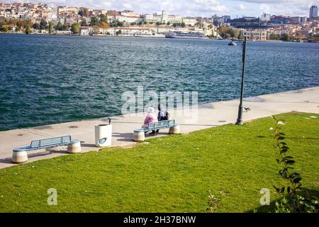 Fatih,Istanbul,Türkei-Oktober-Mittwoch-2021: Frauen in zwei Hüten sitzen auf einer Bank am Goldenen Horn Stockfoto