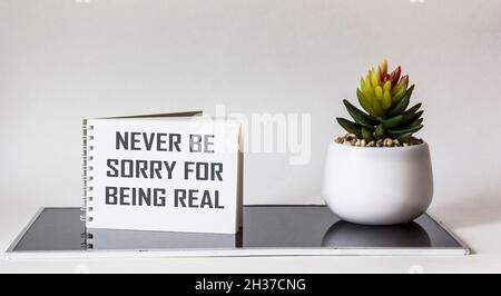Bereuen Sie nie, wirklich zu sein. Inspirierender Satz auf Notizblock, neben einer Kaktusblume auf weißem und schwarzem Hintergrund. Persönliches Entwicklungskonzept Stockfoto