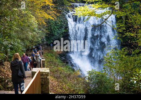 Besucher genießen die wunderschöne Herbstlandschaft bei Dry Falls, einem hinter dem Wasserfall zwischen Highlands und Franklin im Westen von North Carolina. (USA) Stockfoto