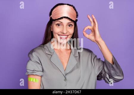 Porträt der schönen trendigen fröhlichen Frau zeigt ok-Zeichen Gips auf der Schulter isoliert über violett lila Farbe Hintergrund Stockfoto