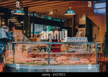 London, Großbritannien - 17. Oktober 2021: Mann, der am Frischfleisch- und Geflügelstand im Borough Market arbeitet, einem der größten und ältesten Lebensmittelmärkte in London Stockfoto