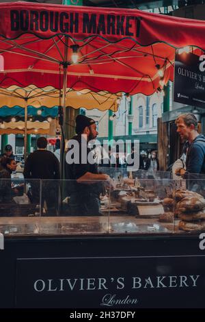 London, Großbritannien - 17. Oktober 2021: Verkäufer und Kunde am Olivers Bakery Stand am Borough Market, einem der größten und ältesten Lebensmittelmärkte in London, SE Stockfoto