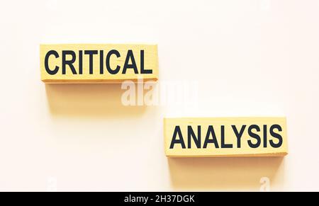 Kritische Analyse - isolierter Text auf Holzblöcken und weißem Hintergrund. Stockfoto