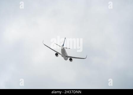 Rückansicht eines weißen Passagierflugzeugs in Nahaufnahme vor einem grauen Himmel mit Kopierraum. Die Ebene bewegt sich nach rechts Stockfoto