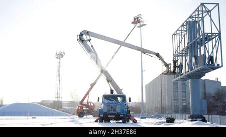 Baumeister auf einer Aufzugsplattform auf einer Baustelle. Männer bei der Arbeit. Bauarbeiter Montage Gerüst auf der Baustelle. Männer montieren Billboard auf Stockfoto
