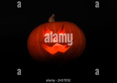 Witzig Gruseliger Halloween Kürbis mit einer Kerze im Inneren isoliert auf schwarzem Hintergrund. Gruselig lächelnd Halloween Kürbis DIY Konzept Stockfoto