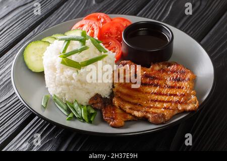 Vietnamesisches Essen gebrochener Reis mit gegrilltem Schweinefleisch und frischem Gemüse aus der Nähe in einem Teller auf dem Tisch. Horizontal Stockfoto