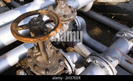 Alte Kraftstoffübertragungsventile an einem Gebäude im Industriegebiet. Lager. Altes Kraftstoffventil im Tanklager Stockfoto