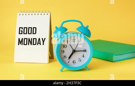 Guten Montag, der Text steht auf einem Notizbuch, neben einer Uhr und einem Tagebuch auf gelbem Hintergrund. Anfang der Woche . Stockfoto