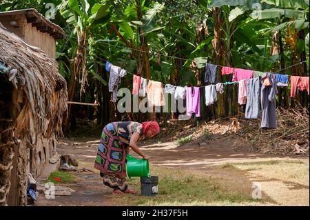 Einheimische Frau mit Wäsche bei einem Dorfspaziergang in Mto wa Mbu, Tansania, Afrika Stockfoto