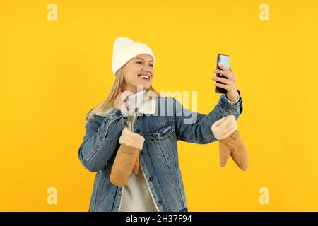 Attraktive Mädchen in Winterkleidung nehmen Sie ein Selfie auf gelben backgroundю Stockfoto