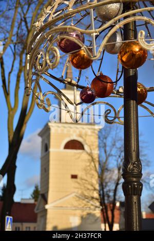 Weihnachtsschmuck vor dem Hintergrund des historischen Glockenturms an einem sonnigen Tag in einer ungewöhnlichen Aufnahme. Stockfoto
