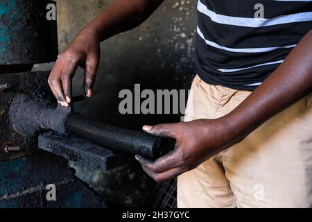 (211026) -- WAKISO, 26. Oktober 2021 (Xinhua) -- Wilbert Twinomujuni, ein Lehrer, entfernt Briketts aus der Kompressormaschine in einer Werkstatt in der St. Kizito High School in Namugongo, Wakiso District, Uganda, 14. Oktober 2021. UM ZU SAGEN: „Feature: Ugandische Lehrer greifen auf Überlebensfähigkeiten zu, da Schulen wegen COVID-19 geschlossen bleiben“ (Foto: Hadarah Nalwadda/Xinhua) Stockfoto